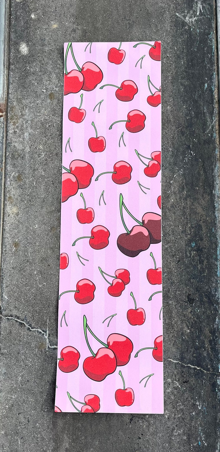 Baffled Panda Cherry graphic skateboard grip tape photographed on skatepark concrete
